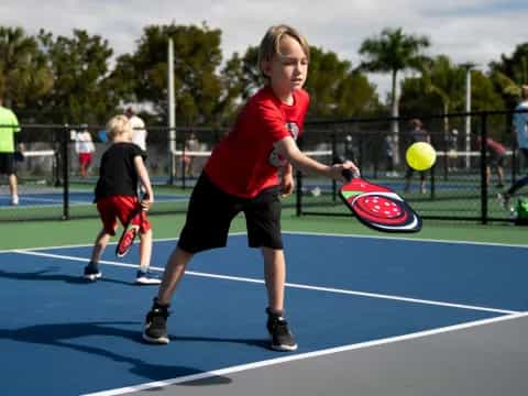 a boy hitting a ball with a racket