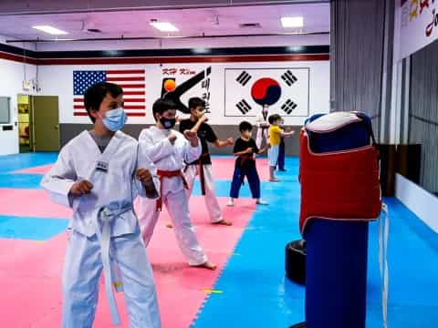 a group of people in white karate uniforms in a room with a red and blue wall and a