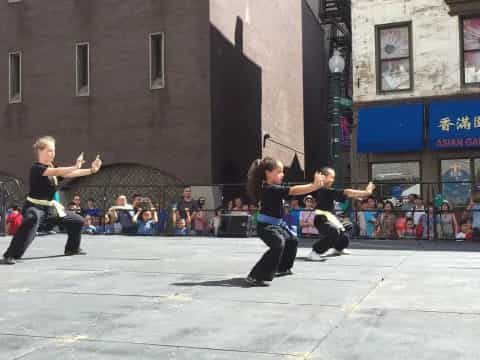 a group of people in black uniforms dancing in front of a crowd