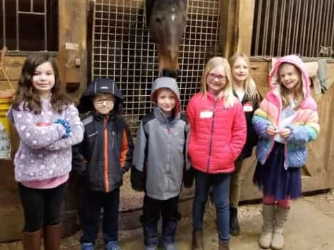 a group of children posing for a photo in front of a horse