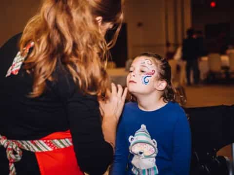 a person with paint on the face and a girl with the hand on the face