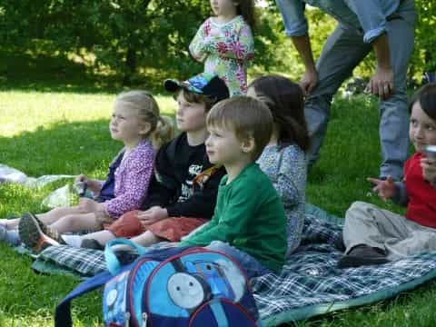 a group of children sitting on the grass