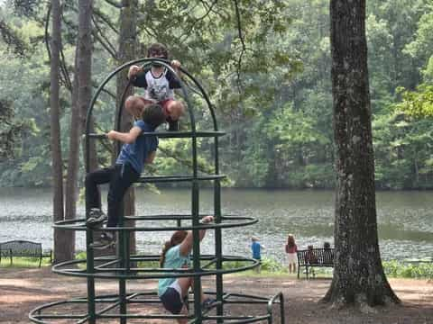 a group of people playing on a playground set by a lake