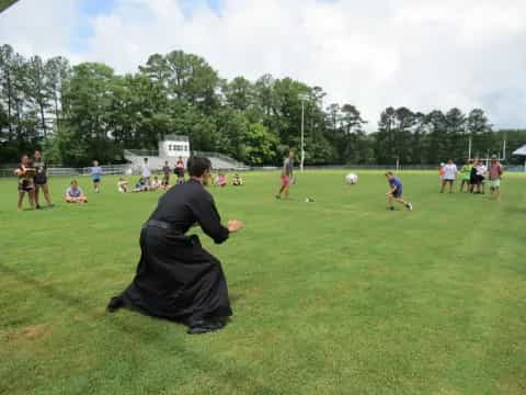 a person kneeling on the grass with a football ball in front of him