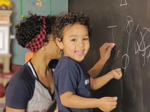 a young girl and a young boy writing on a blackboard