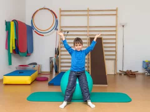 a boy standing on a mat in a room with a play set