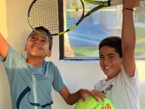 a couple of boys holding tennis rackets