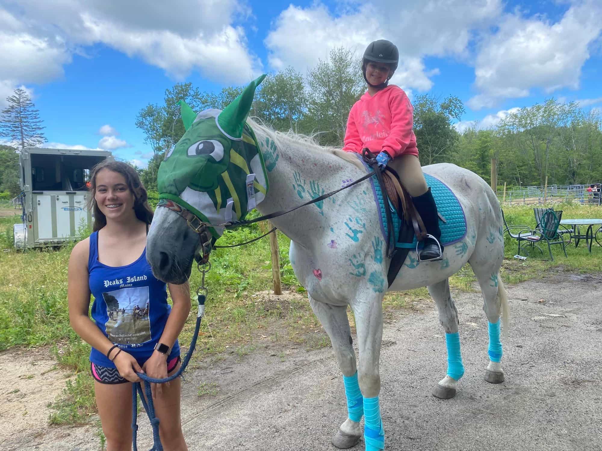 a person standing next to a girl on a horse
