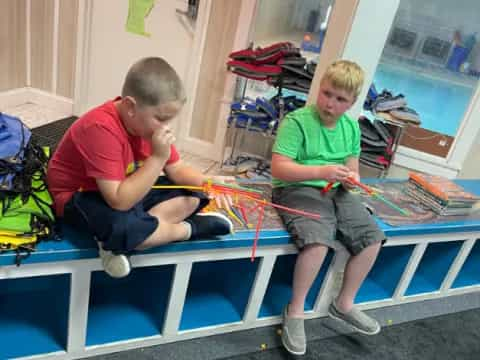 a couple of boys sitting on a mat playing a board game