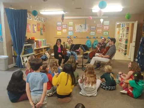 a group of people sitting in a room playing instruments