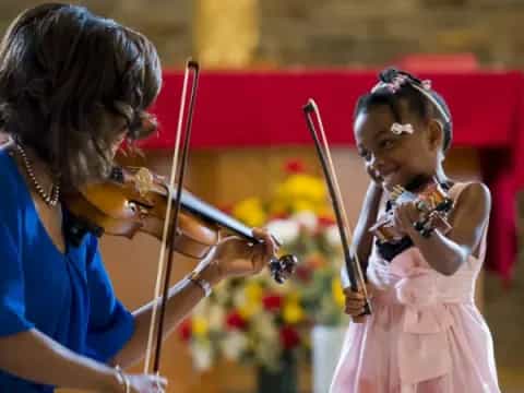 a person playing a violin next to a young girl
