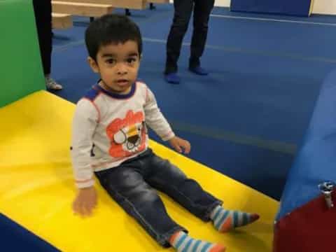a boy sitting on a yellow mat