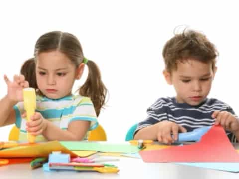 a boy and girl coloring on a table