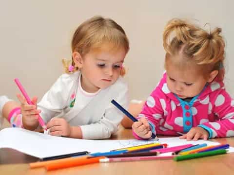 a couple of young girls writing on paper