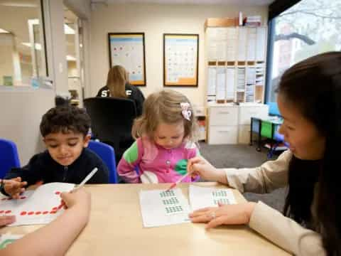 a person and a couple of children sitting at a table