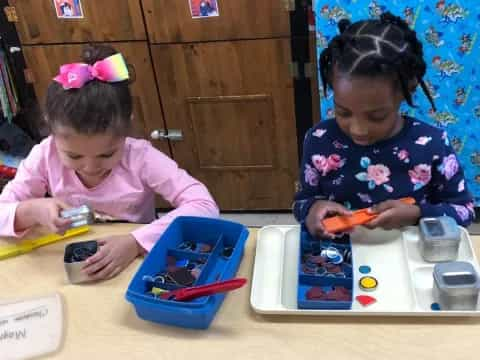 a couple of young girls playing with toys on a table