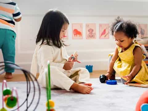 a couple of young girls playing with toys on the floor