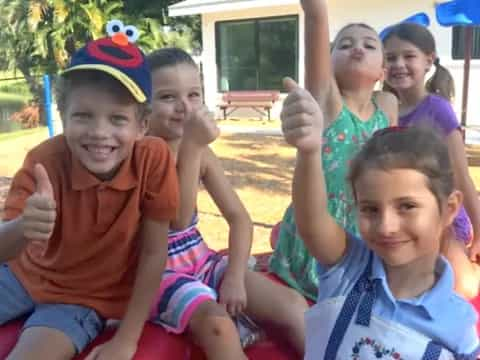 a group of kids sitting on a red and white chair in a park