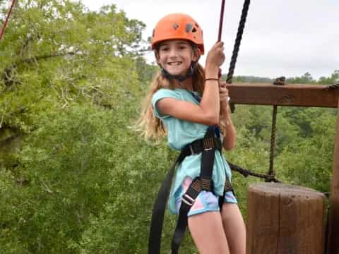 a girl wearing a helmet and climbing a rope