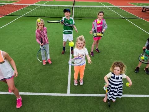 a group of kids playing tennis