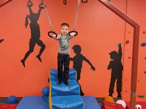 a boy standing on a swing set