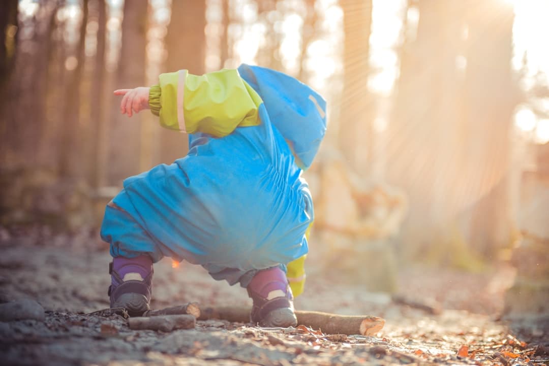 toddler picking up tree branch