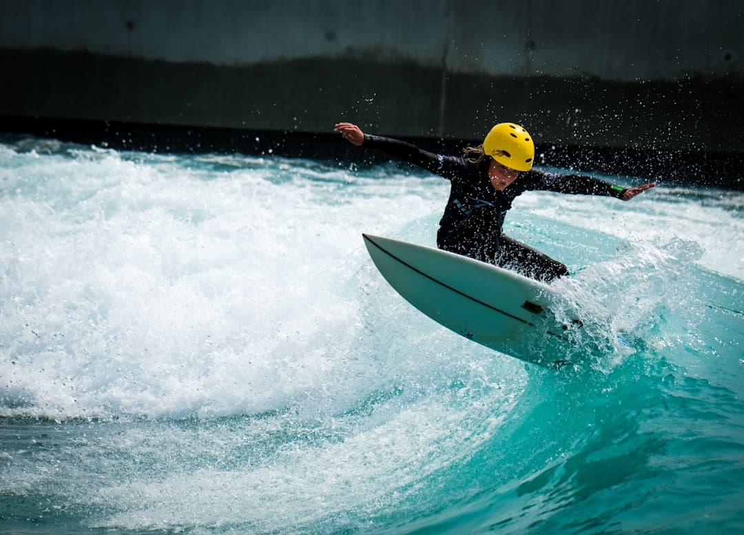 man in yellow life vest riding white surfboard during daytime