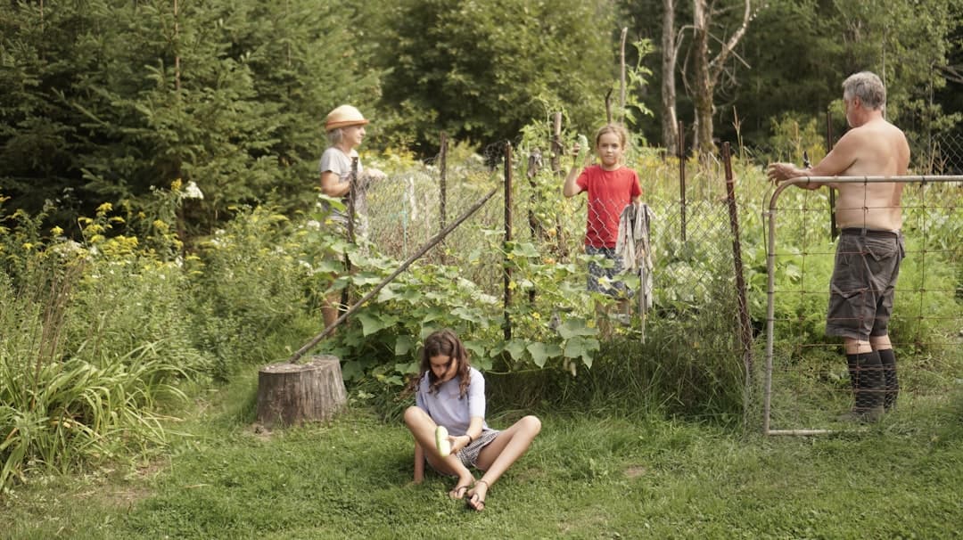 a woman sitting on the ground in front of a garden