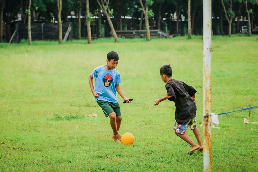 a couple of young men kicking around a yellow soccer ball