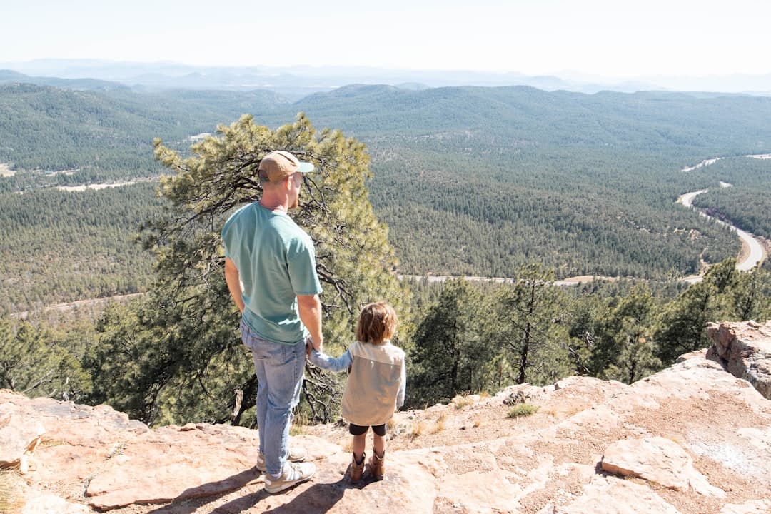 a man and a child walking on a rock ledge overlooking a valley