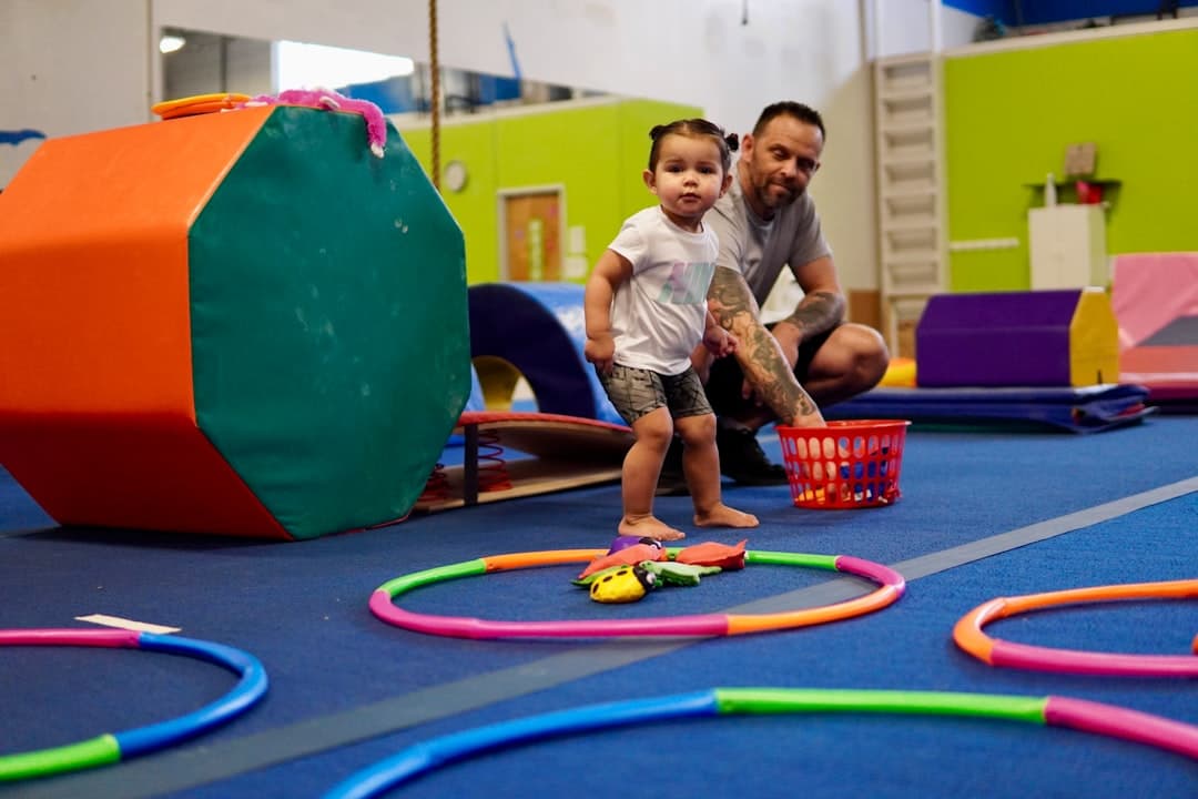 a person and a child playing with toys on a blue mat