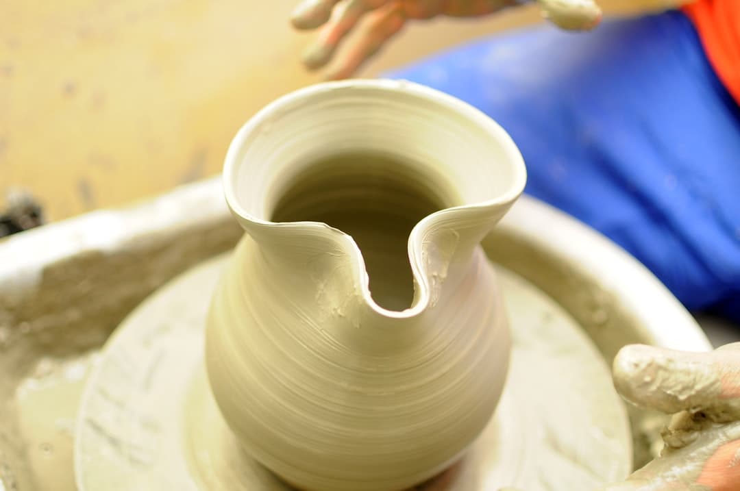 a person making a vase on a potter's wheel