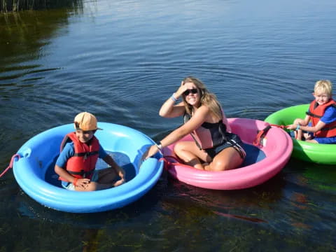 a woman and two kids in kayaks on a lake