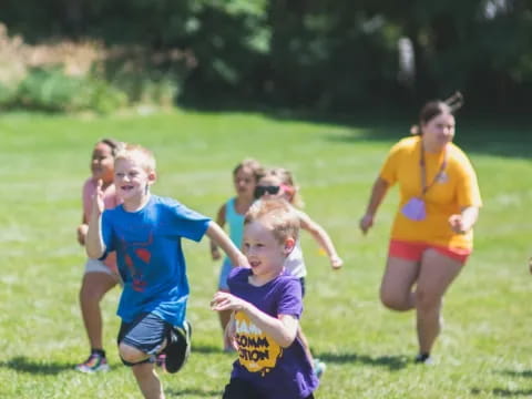 a group of kids running on a grass field