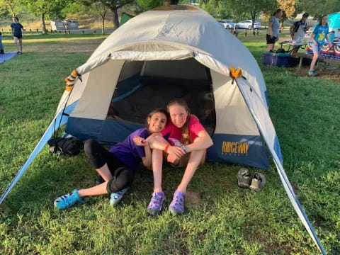 two girls sitting in a tent