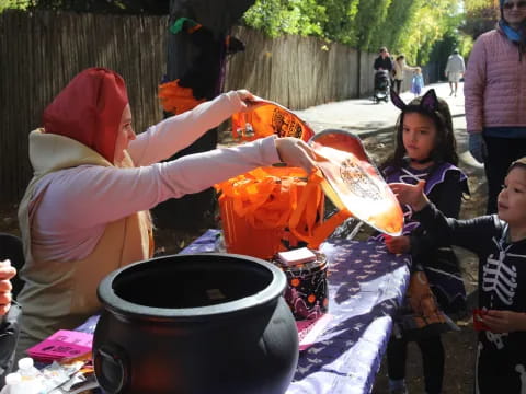a person pouring a liquid into a bucket with children around the