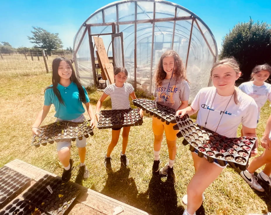 a group of girls posing for a picture in front of a large metal ball