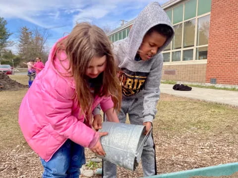 a couple of children playing with a water fountain outside