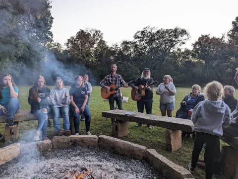 a group of people sitting on a bench with a person playing guitar