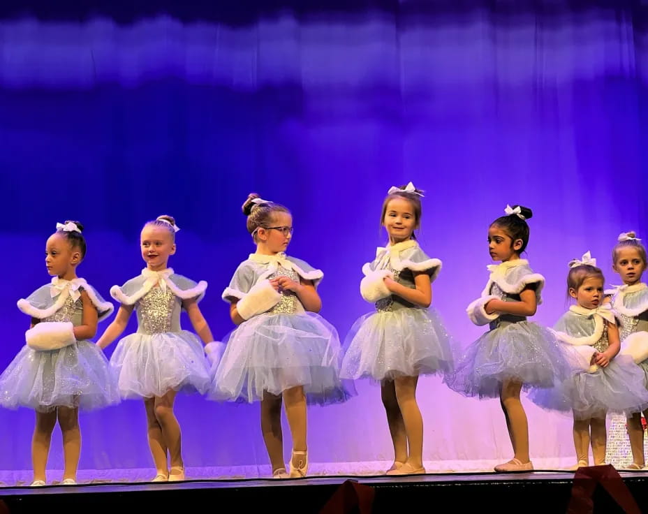 a group of girls in dresses on a stage