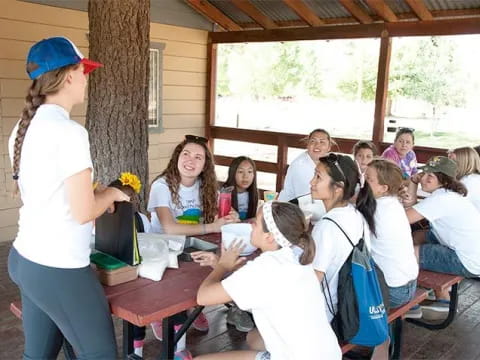 a woman standing in front of a group of people sitting at tables