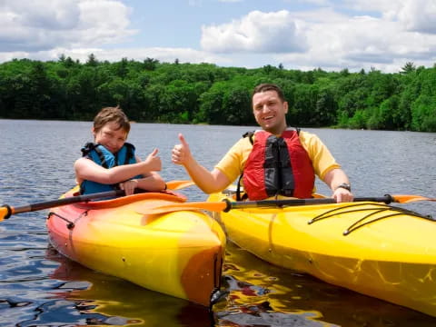 a person and a boy in a yellow kayak on a lake