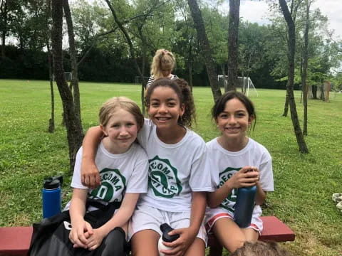 a group of girls sitting on a bench in a park