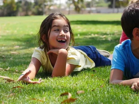 a boy and girl playing in the grass
