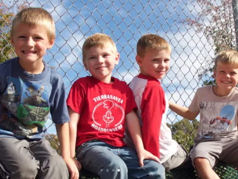 a group of boys sitting on a fence