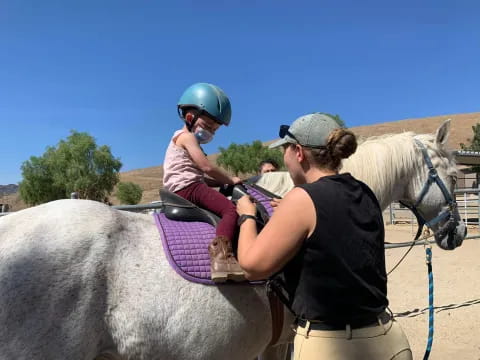 a person riding a horse with a child on the back