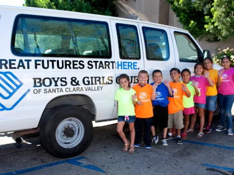 a group of children posing for a photo in front of a white van