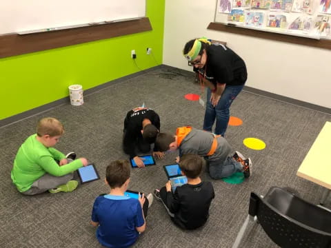 a group of people sitting on the floor looking at a tablet