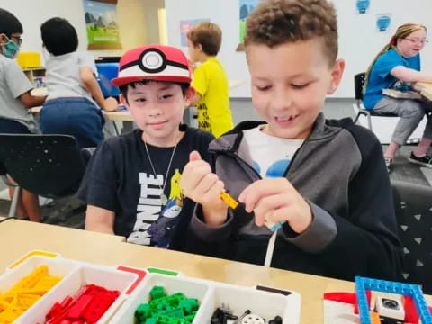 a couple of boys sitting at a table with toys