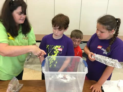 a group of children looking at a plastic container